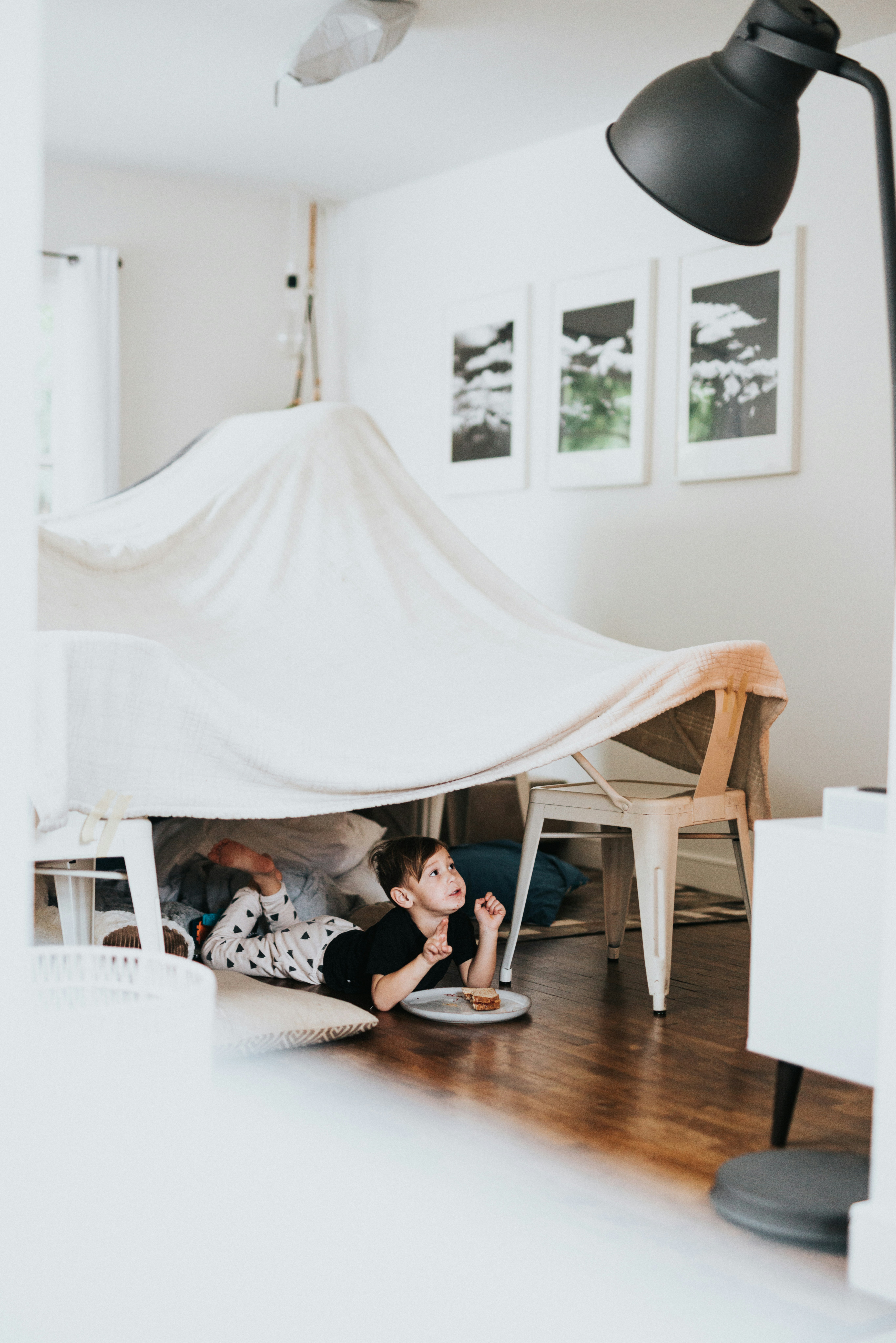 a child in a den made of sheets in a living room