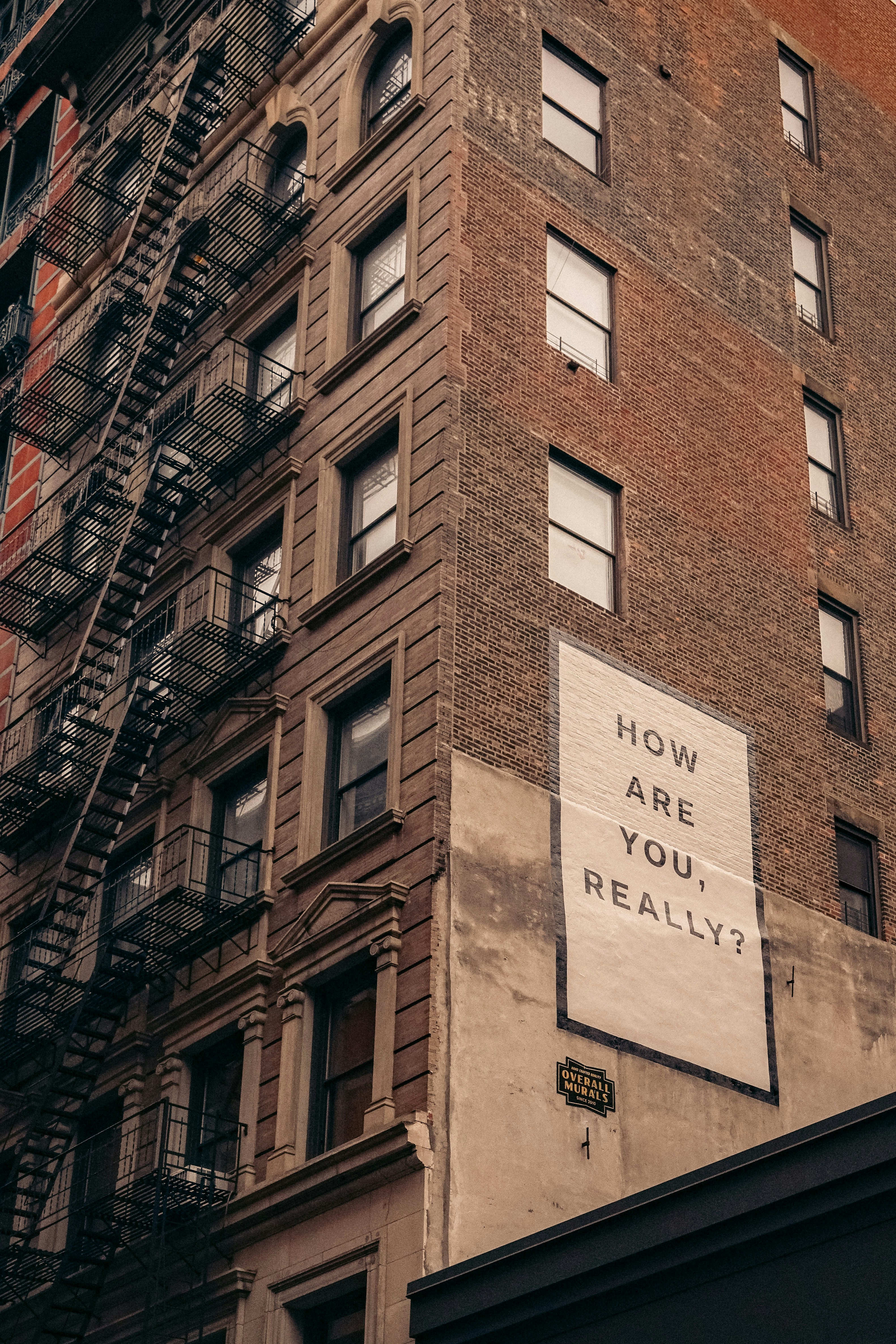 A painted sign on a building asking: how are you, really?