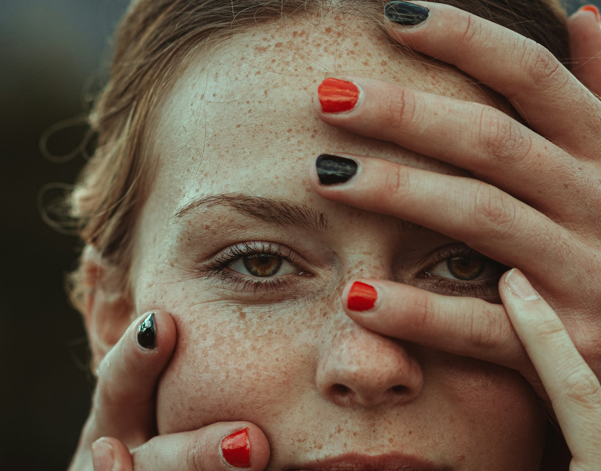 a close portrait of a young woman with her hands over her face